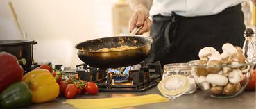 Persoon kookt met pan in de hand op een gasvuur, Primagaz
