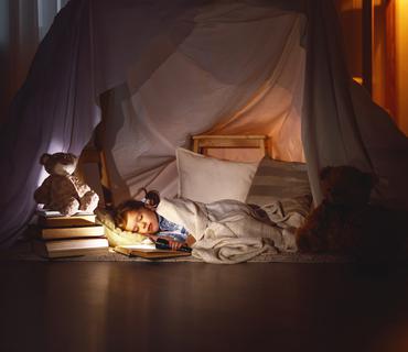 Slapend kind in zelfgebouwd kamp van kussens 