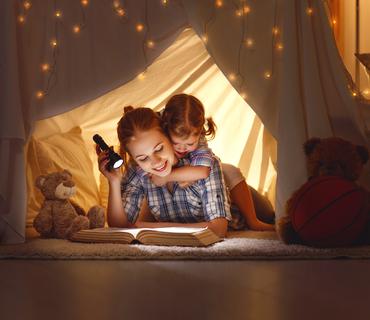 Moeder leest voor aan kind met zaklamp