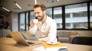 Zakenman drinkt koffie aan zijn laptop