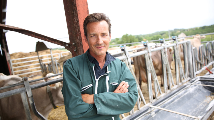 Landbouwer poseert met gekruiste armen in stallen